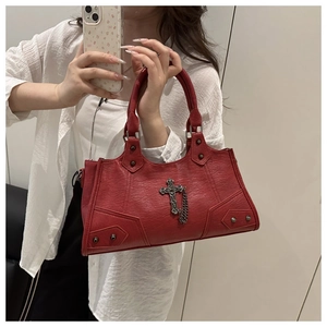 Detail der dunkelroten Motorradtasche mit großem Metallkreuz-Anhänger und Silbernieten