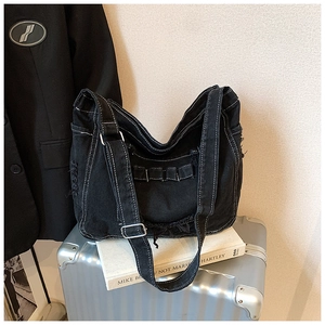 Detail of vintage black denim tote bag with contrast white stitching and frayed edges