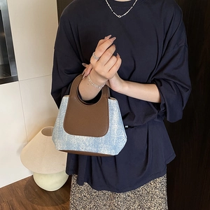 Retro denim bucket bag with brown leather trim shown in a stylish lifestyle setting