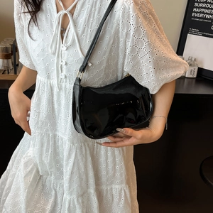Minimalist black patent leather underarm bag with glossy finish and elegant half-moon shape