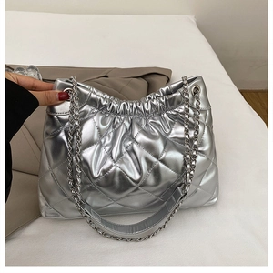 Détail de la texture matelassée argentée et de la bandoulière en chaîne du sac fourre-tout