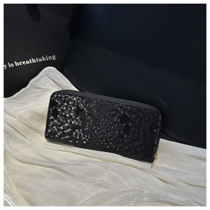 Close-up of black snakeskin texture with metallic finish and gold zipper on long wallet
