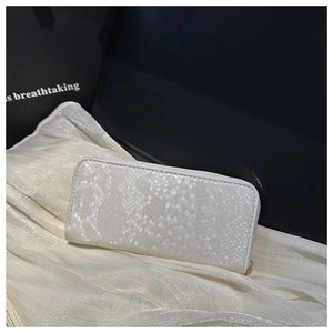 Detail view of white snakeskin texture long wallet with gold zipper on silk fabric