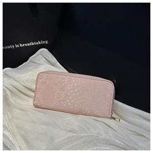Detail of light pink snakeskin texture long wallet with gold zipper on white fabric