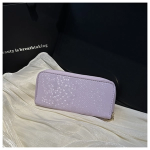Detailed view of lavender snakeskin wallet with golden zipper on white fabric background