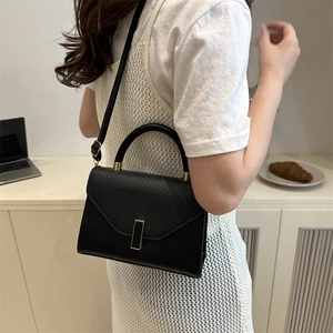 Schicke schwarze PU-Handtasche mit Klappe in Eidechsen-Optik und Goldschnalle an Model in Weiß