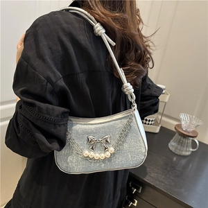 Sparkling light blue shoulder bag with silver butterfly and pearl chain on a female model