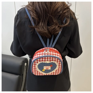 Ragazza che indossa un mini zaino a quadretti con toppa a cuore e pizzo fine