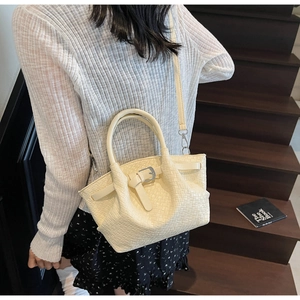 Dettaglio di una borsa a secchiello intrecciata bianco crema con fibbia e tracolla