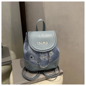 Close-up of light blue mini backpack featuring teddy bear embroidery and silver chain detail