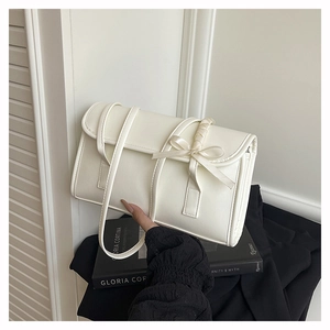 Detailed macro view of cream white shoulder bag with decorative bow and smooth texture