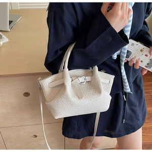 Dettaglio della borsa a secchiello in pelle intrecciata bianca con tracolla e finitura