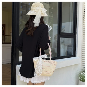 Detail of woven straw tote bag and sun hat with elegant white lace bow decoration