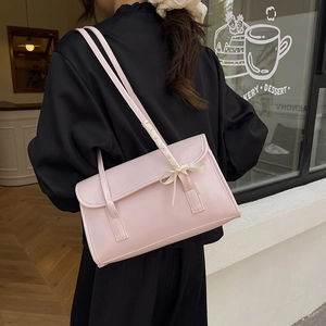 Pink ballet style baguette shoulder bag with ribbon bow and thin straps on model