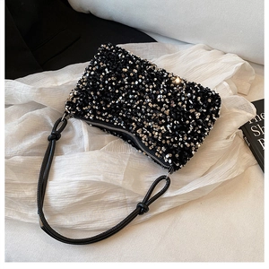 Dettaglio della borsa a tracolla con paillettes nere, trama lucida e tracolla con nodo