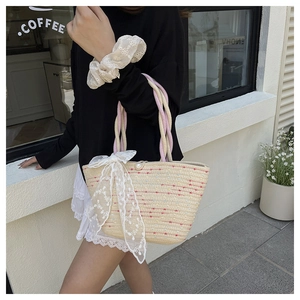 Detail of hand-woven straw bucket bag with colorful dots, lace bow and pearl closure