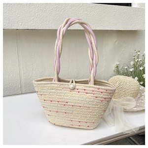 Detail of woven bucket bag with pearl closure and colorful pink twisted handle