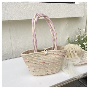 Close-up of woven bucket bag featuring colorful dots, pearl button, and braided handle