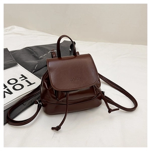 Close-up of small brown synthetic leather backpack with drawstring closure and flap cover