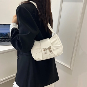 Sac à bandoulière blanc plissé avec boucle papillon porté par une femme au bureau