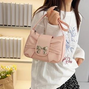 Sac à bandoulière rose plissé avec nœud et fermoir argenté porté par un mannequin chic