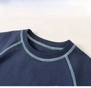 Detail view of navy blue crew neck t-shirt with light blue contrast stitching on sleeves