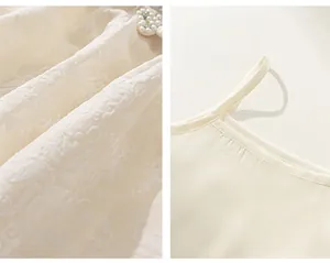 Détail d'une robe pour enfant crème avec gaufrage floral 3D et accents de perles