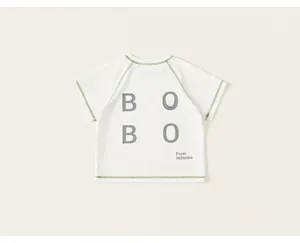 Detail of kids cream t-shirt with green contrast stitching and grey BOBO letter print