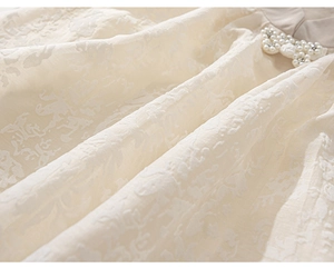 Détail du tissu jacquard floral crème avec élégante décoration de perles et de strass