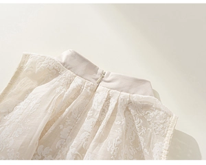 Détail de robe blanche pour fille avec col officier et tissu jacquard floral texturé