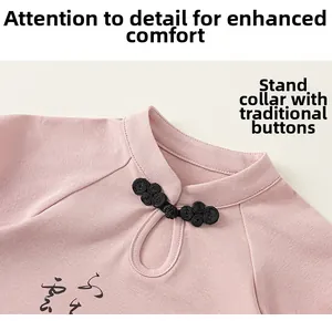 Détail d'une tenue chinoise rose pour enfant avec bouton chinois noir et calligraphie