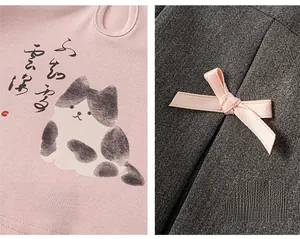 Détail du tissu en maille rose avec motif chat et jupe grise ornée d'un nœud en satin