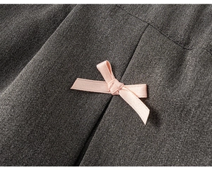 Détail de la texture du tissu sergé gris foncé avec un délicat nœud en satin rose