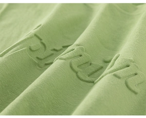 Detailed macro shot of light green cotton fabric with 3D puff print lettering design