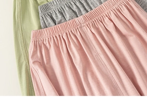 Close-up of cotton kids' pants featuring elastic waistbands in pink, gray, and green