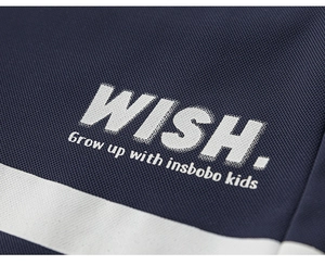 Detail of navy blue fabric with white WISH letter print and striped hem for kids outfit