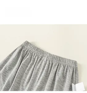 Detail of grey knitted trousers featuring elastic waistband and fine stitching texture