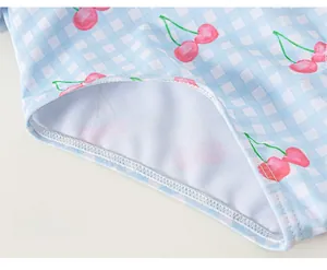 Détail de la couture précise et de l'imprimé cerise sur le maillot de bain fille