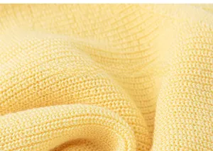 Detailed macro view of the warm yellow knit fabric texture on a girl sleeveless top