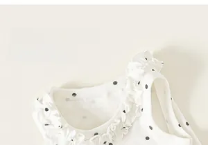 Détail du tissu en coton blanc à pois noirs avec bordure volantée délicate