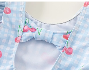 Détail d'un maillot de bain fille à carreaux bleu clair avec imprimé cerise et nœud décoratif