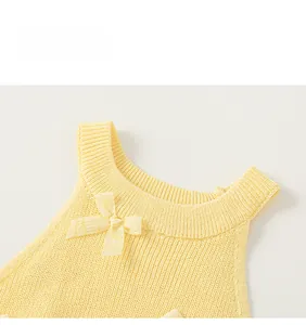 Close-up of yellow knit baby top featuring a ribbed neckline and a cute plaid bow detail