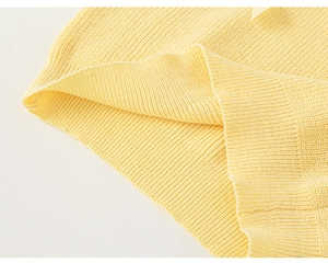 Detailed close-up of light yellow knitted tank top showing ribbed hem and fabric texture