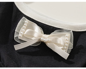 Detail of knit neckline with bow, satin ribbons and pearls on a summer dress
