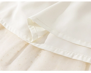 Macro detail of the white plain fabric hem with golden shimmering tulle mesh layers