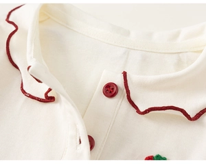Close-up of baby cotton shirt collar with red wavy embroidery and small red buttons