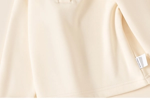 Detailed close-up of cream cotton fabric with smooth stitching and side label tag