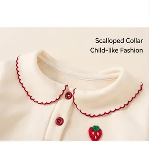 Close-up of girls' white fleece top with red wavy lace collar and strawberry patch