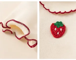 Detail of kids top showing red ruffled cuffs, warm fleece lining and strawberry embroidery
