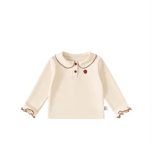 Detail view of cream long sleeve kids top with red scalloped collar and strawberry embroidery